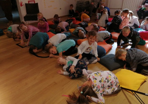 Dzieci leżą na podłodze i naśladują czynności prowadzącej